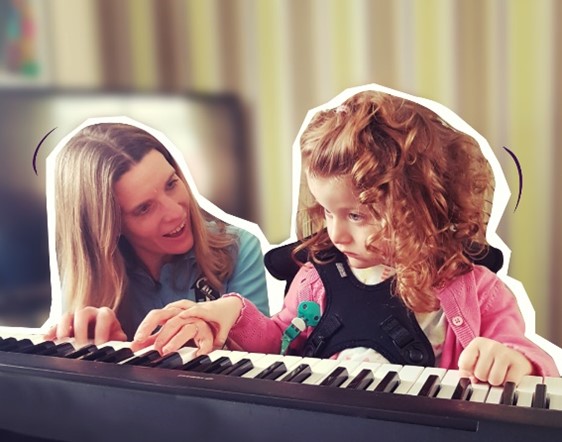 A young girl is shown how to play keyboard by a volunteer from Thomas' Fund