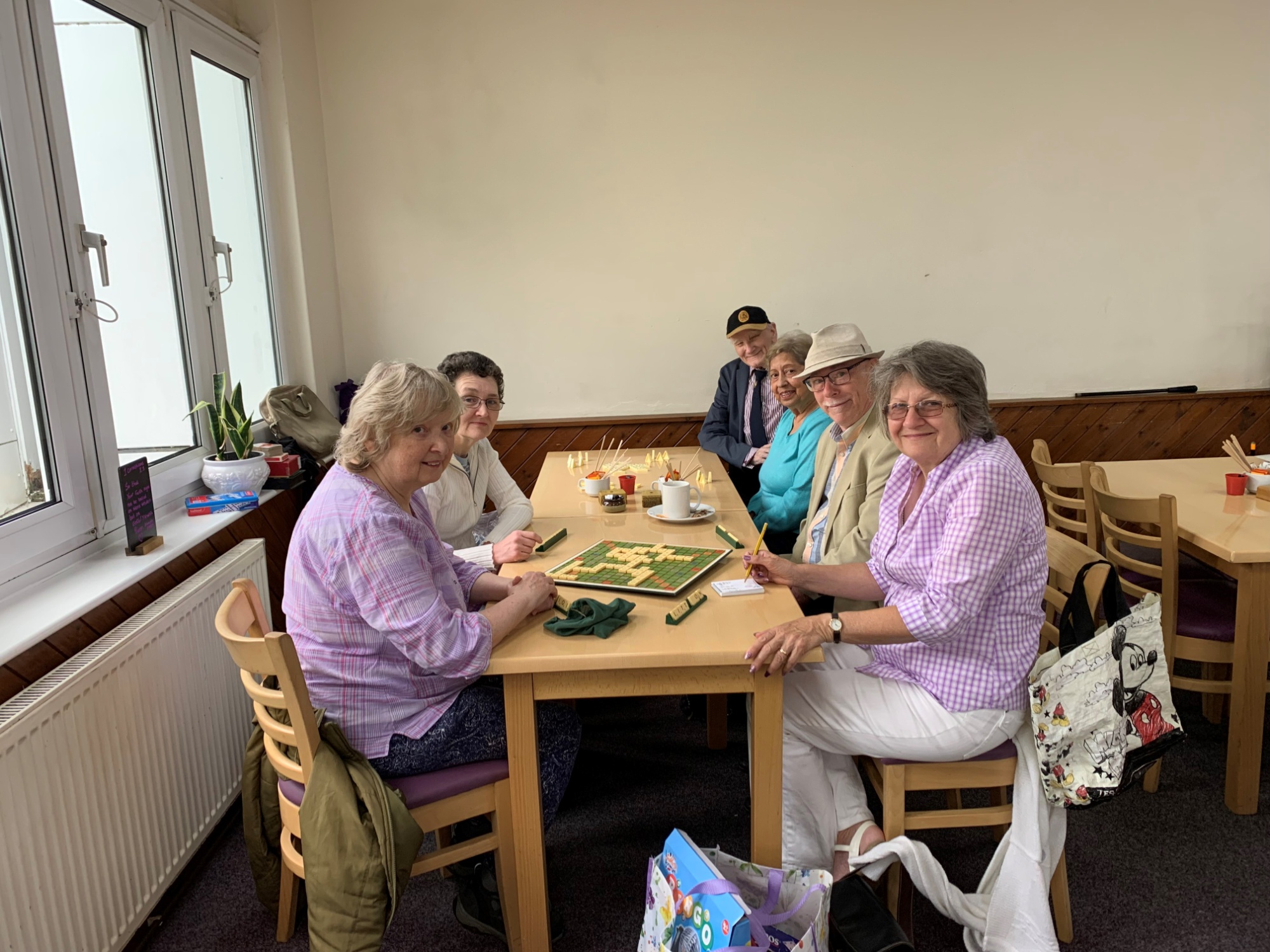 A group of 6 sit around a rectangular table playing board games