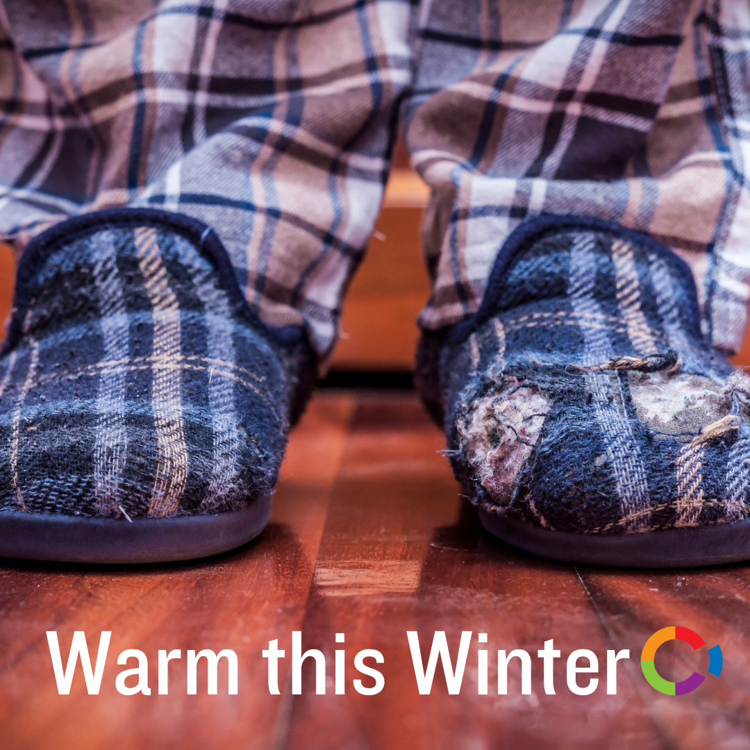 Worn blue slippers with holes worn by someone in checked pyjama bottoms, with the Warm this Winter title underneath