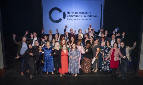 A group of people on stage with their arms in the air, celebrating the Northamptonshire Community Foundation Annual Awards 2022